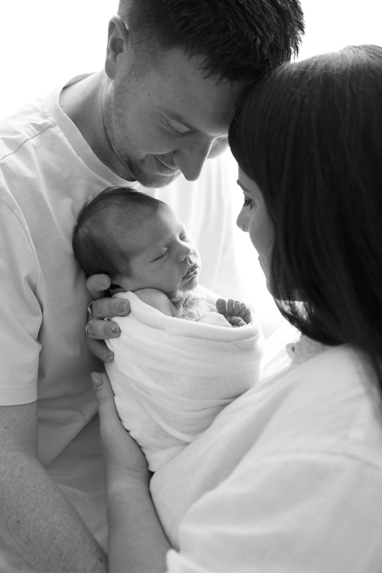 Intimate black and white portrait of parents with sleeping newborn.