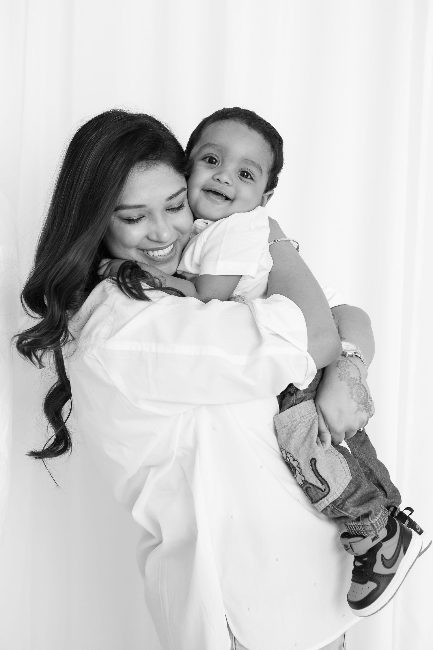 Black and white portrait showing tender moments between parent and child against white background.