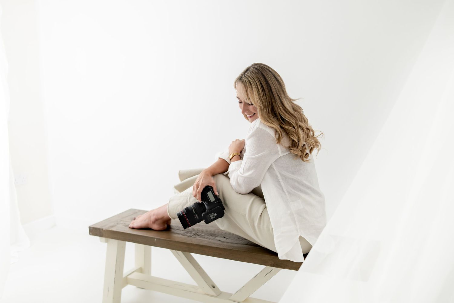 Minimalist white studio maternity photography setup with chair and backdrop.