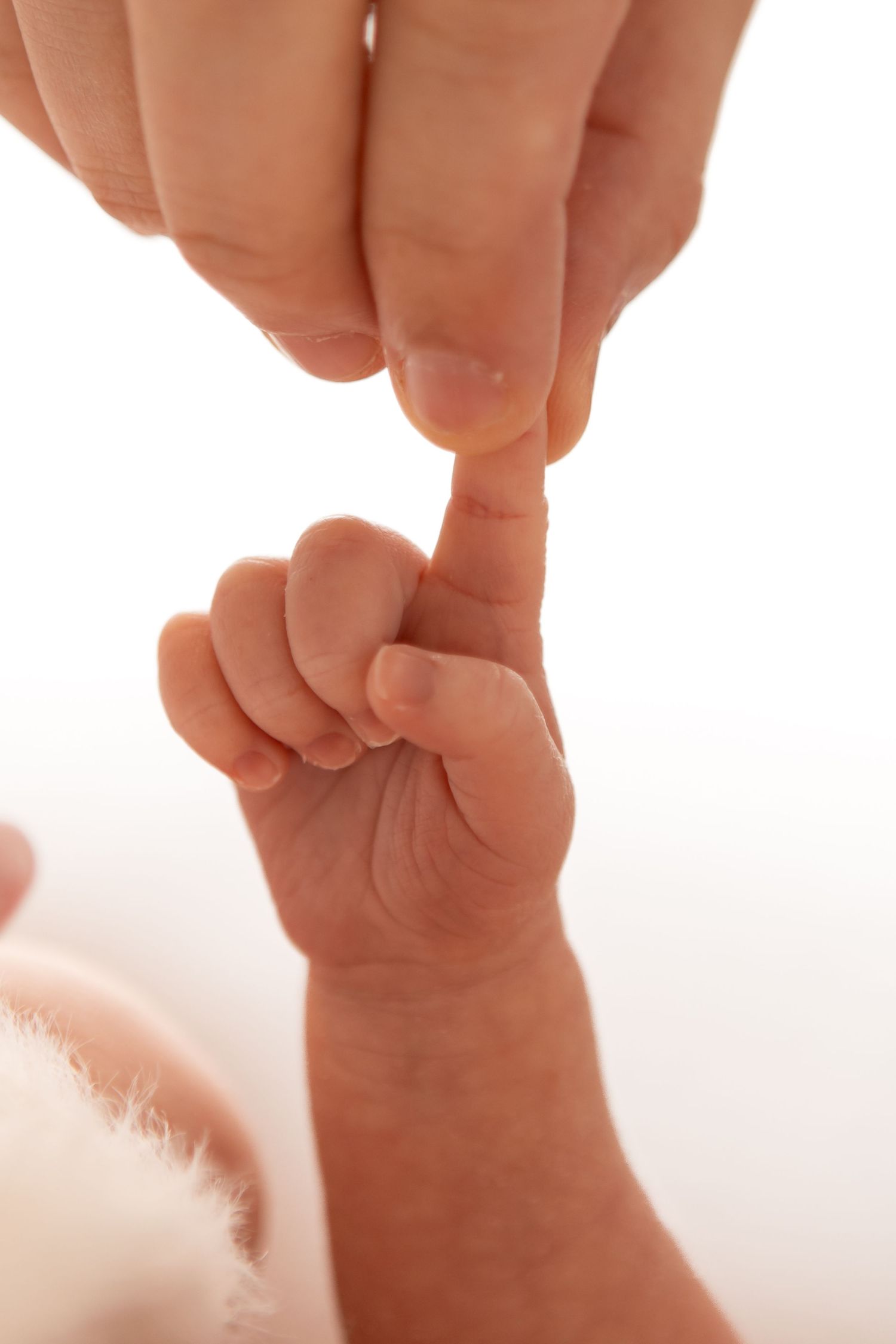 A newborn baby grasping an adult finger with tiny hand, symbolizing trust and parent-child bond.