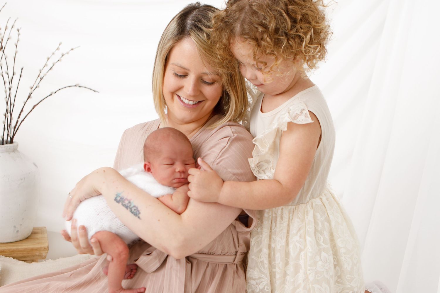 Family sharing tender moment in bright white studio setting.