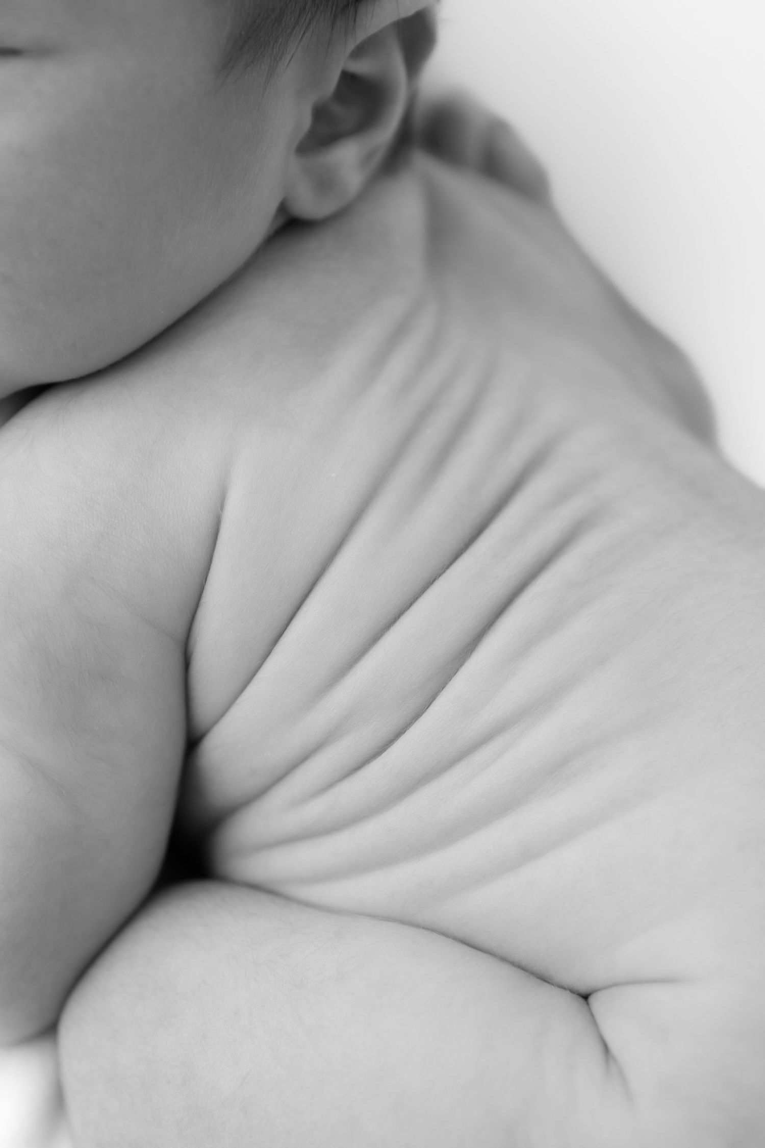 Close-up black and white photograph of delicate baby skin folds and wrinkles creating abstract patterns.