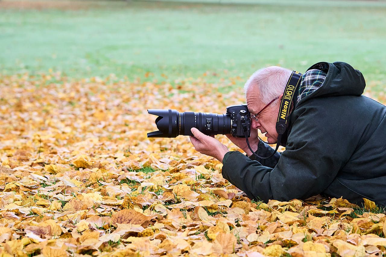 Stages et Formations Photo en Yvelines : un stagiaire photo en action - couché sur le sol et visant dans son appareil photo