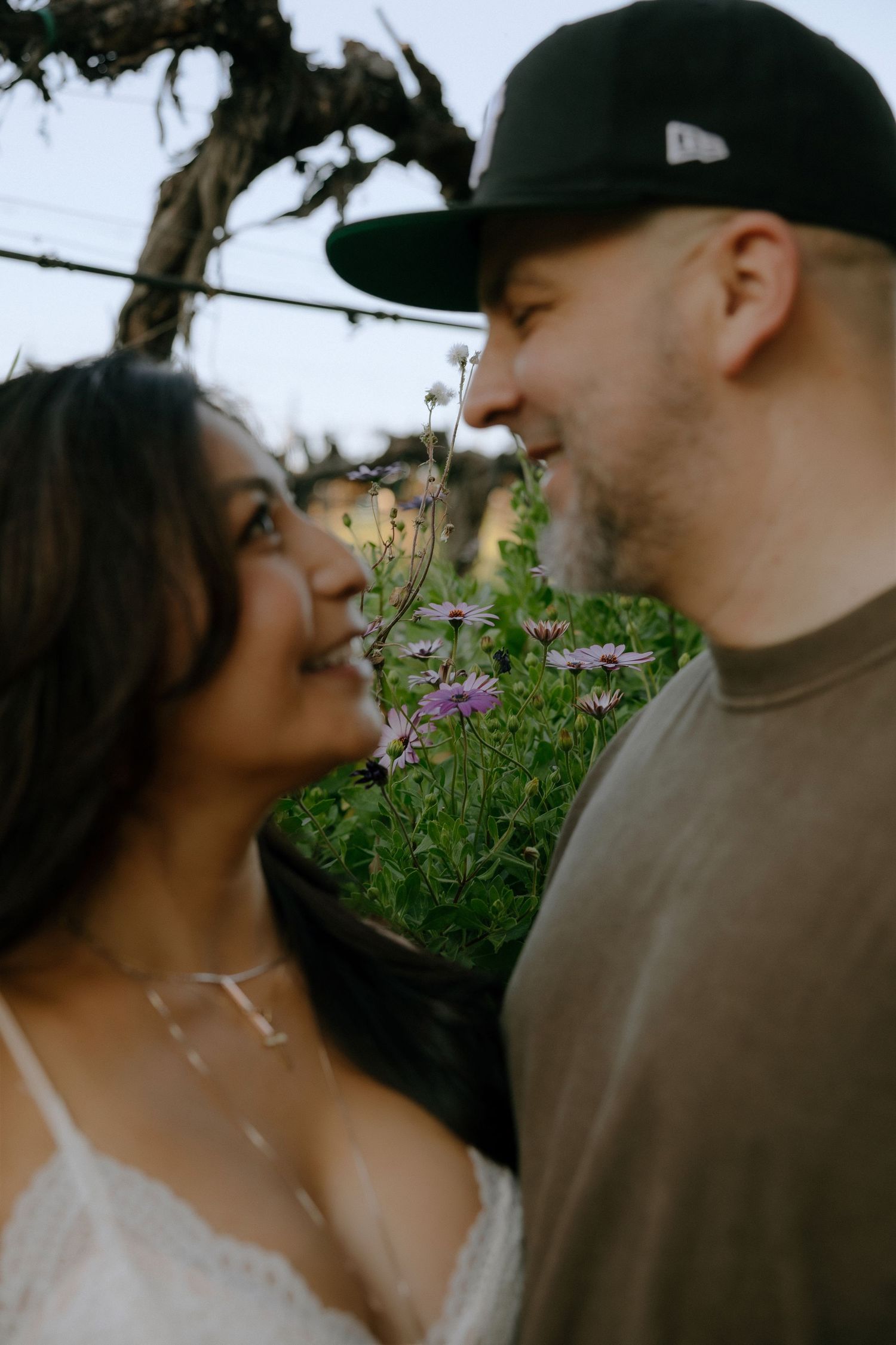 A couple shares an intimate moment together outdoors among blooming wildflowers.