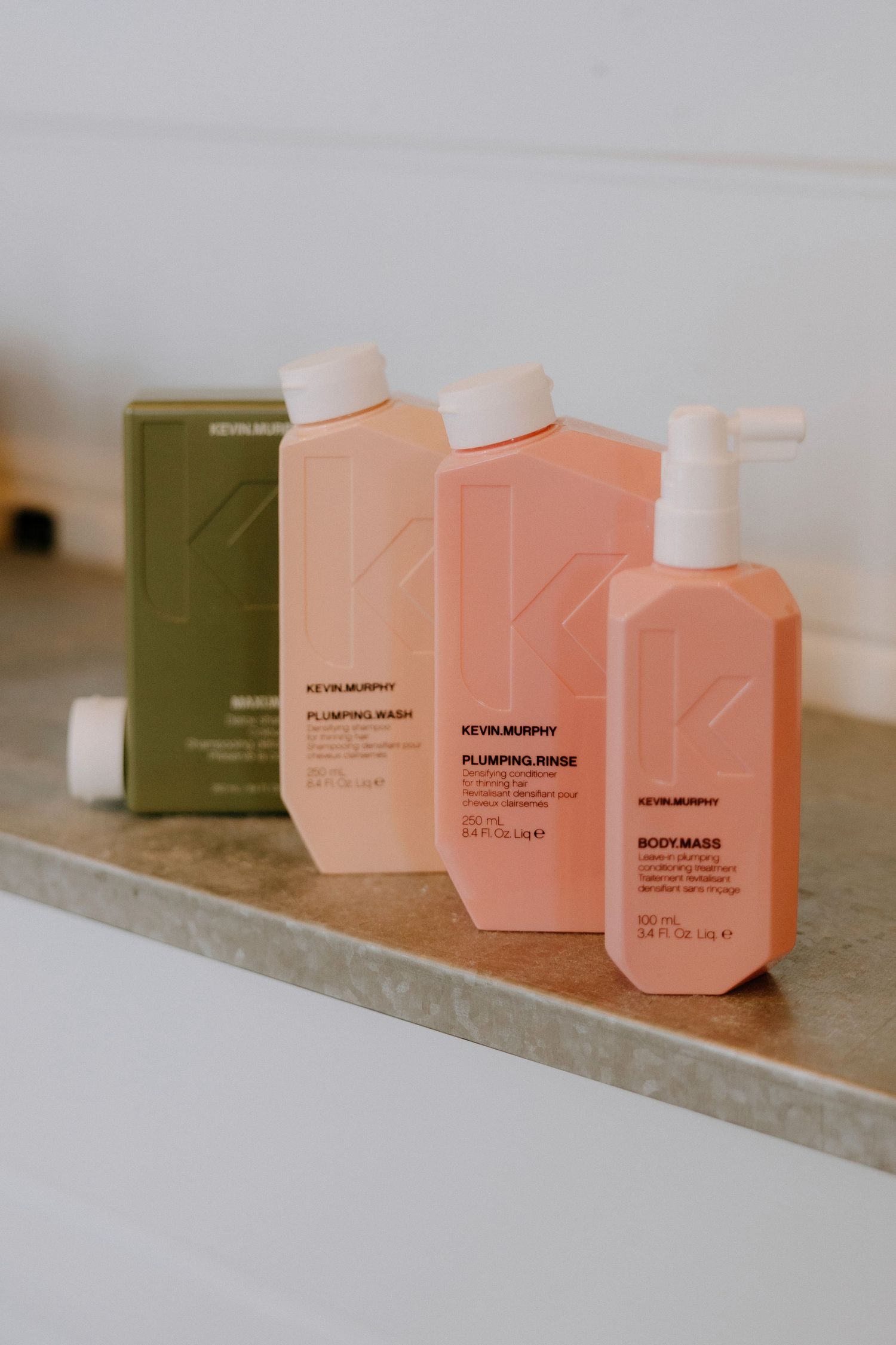 Kevin Murphy Plumping Wash, Plumping Rinse, and Body Mass hair care products displayed on a shelf.