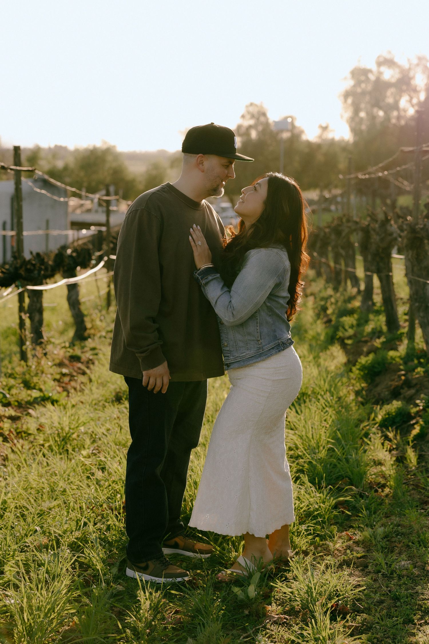 A romantic couple embraces in a sun-drenched vineyard during golden hour creating an intimate moment.