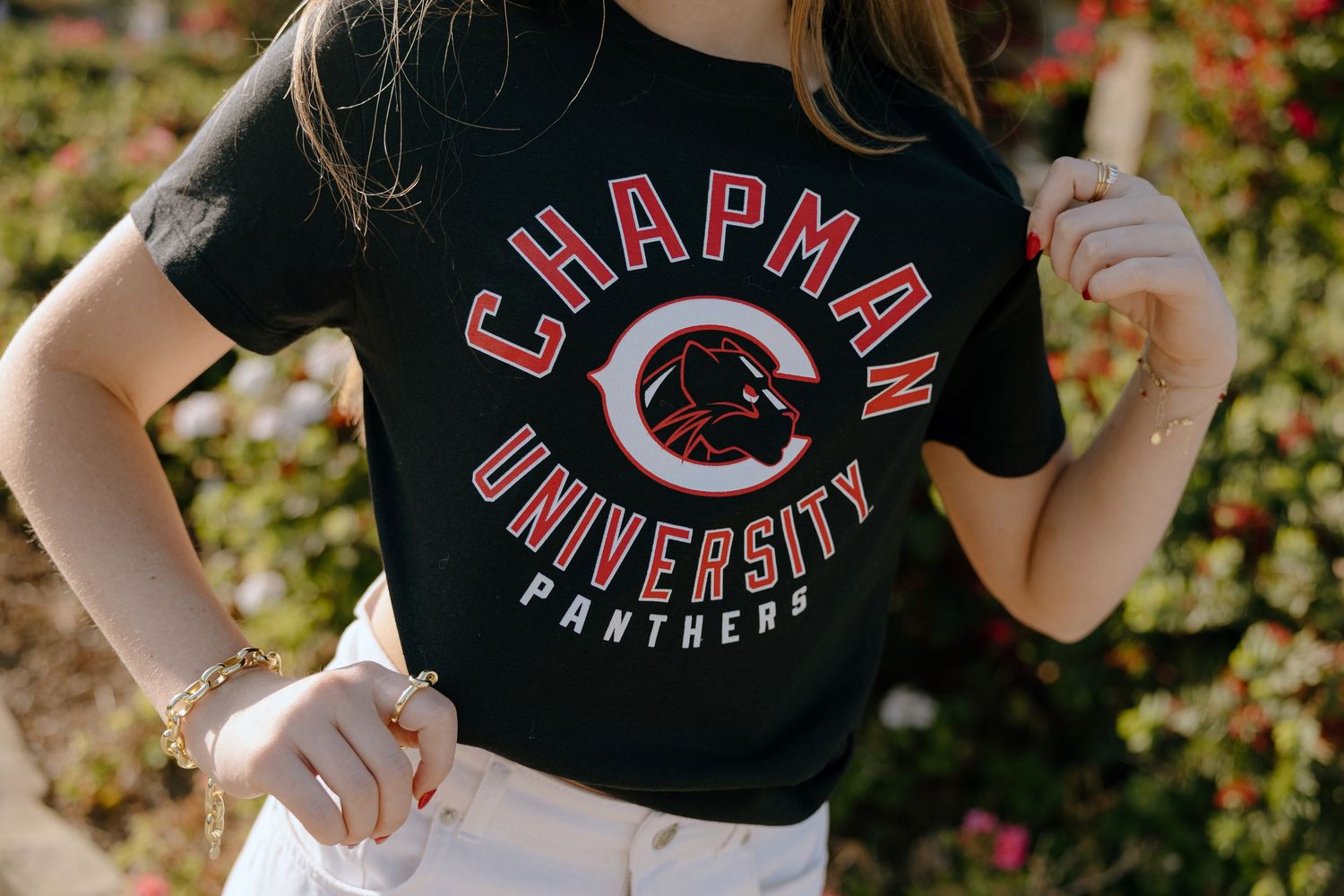 Woman wearing a black Chapman University Panthers graphic t-shirt with red and white lettering outdoors.