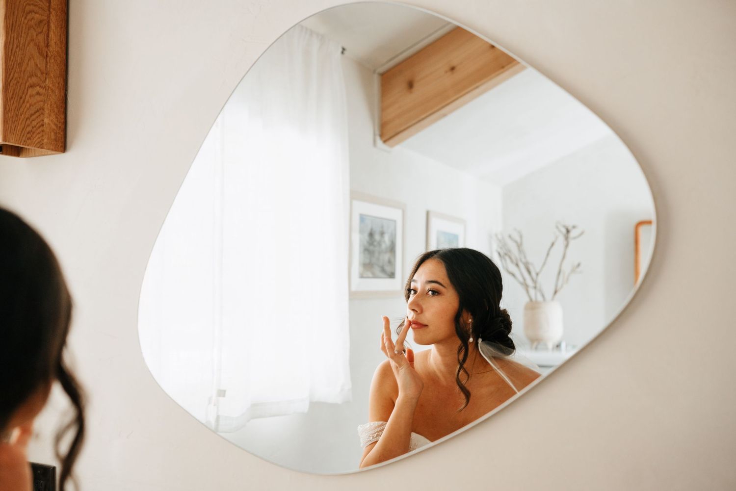 Getting ready scene reflected in oval mirror mounted on wooden wall.
