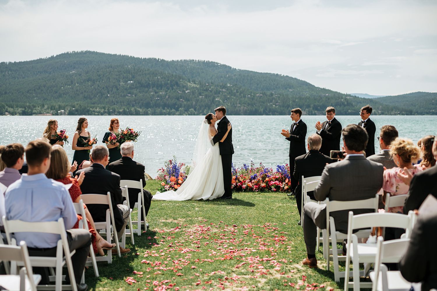 Outdoor wedding ceremony setup with white chairs and mountain vista in background at The Lodge at Whitefish Lake.