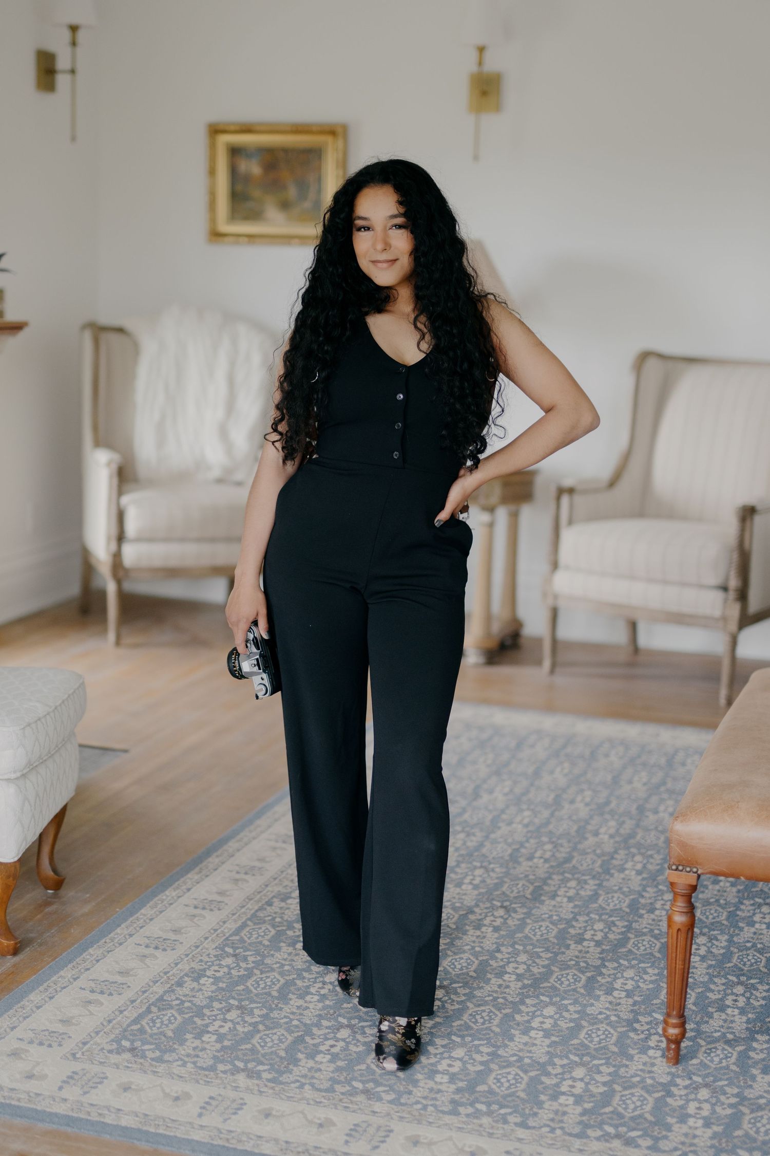 Person in black outfit dancing and posing in elegant room with vintage furniture.