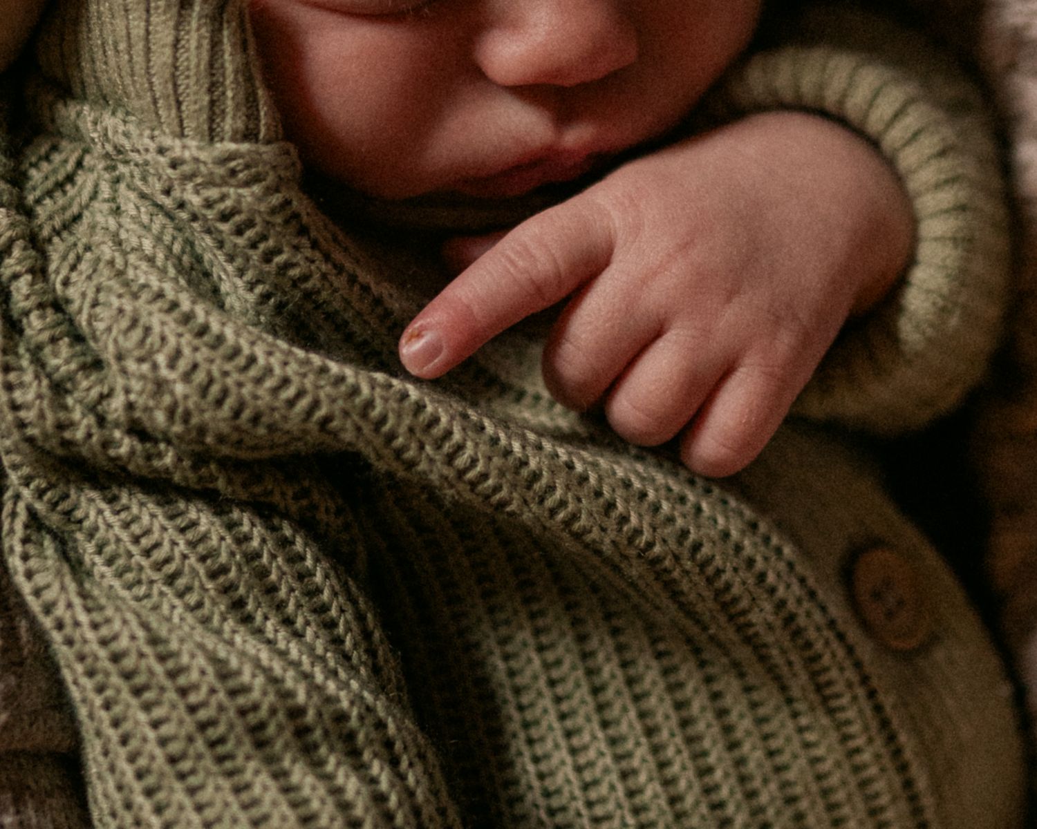 Close-up macro photo of a newborn's hand and mouth.