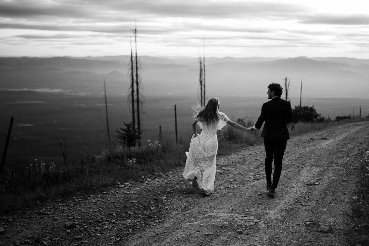 Silhouettes of a couple walking together on a rural path at sunset in black and white.