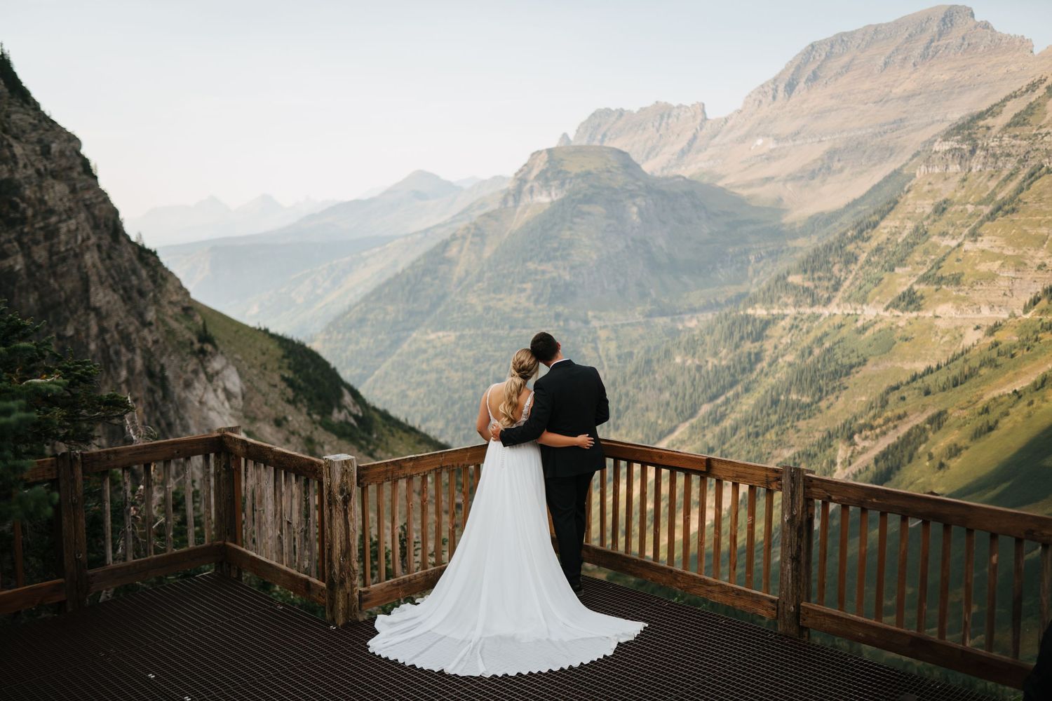 Dramatic mountain landscape wedding photos on wooden observation deck.