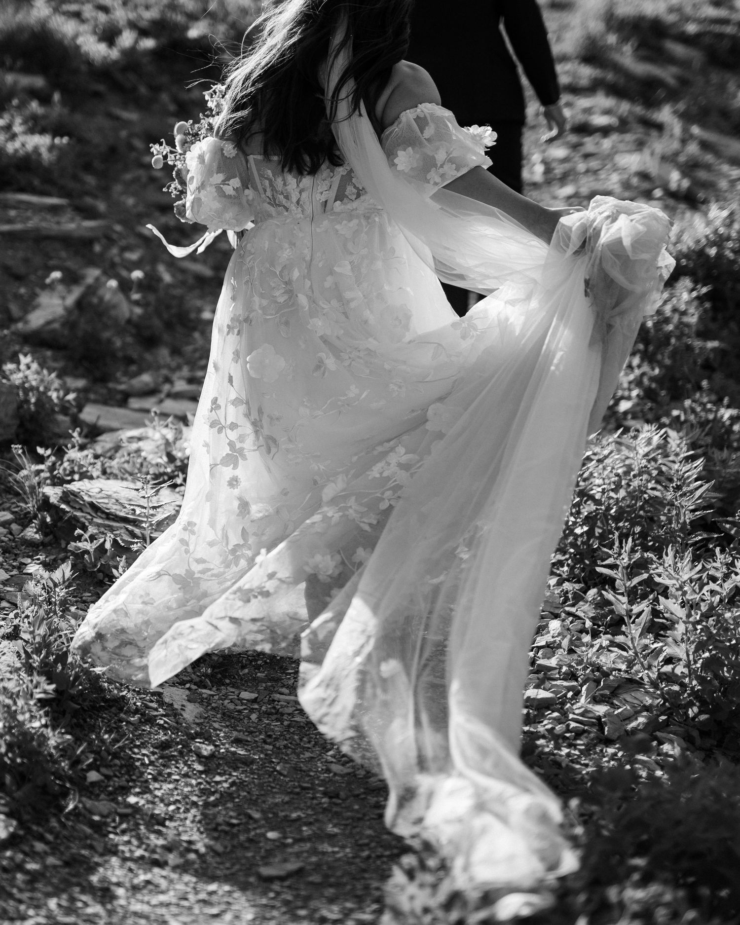 A black and white photo of a flowing white dress twirling in motion against a natural outdoor background.