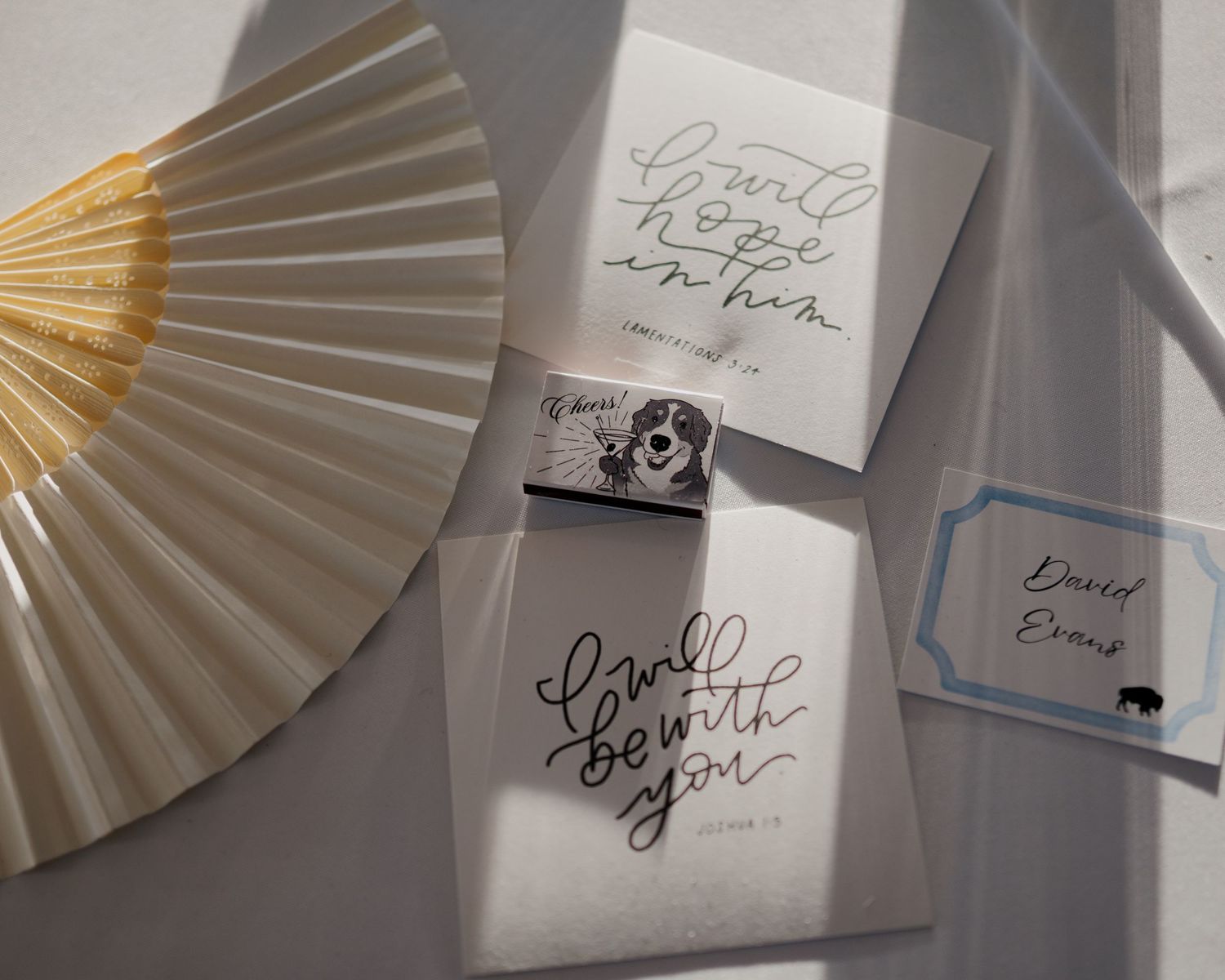 White paper hand fans with black calligraphy writing arranged in a row on a light surface.