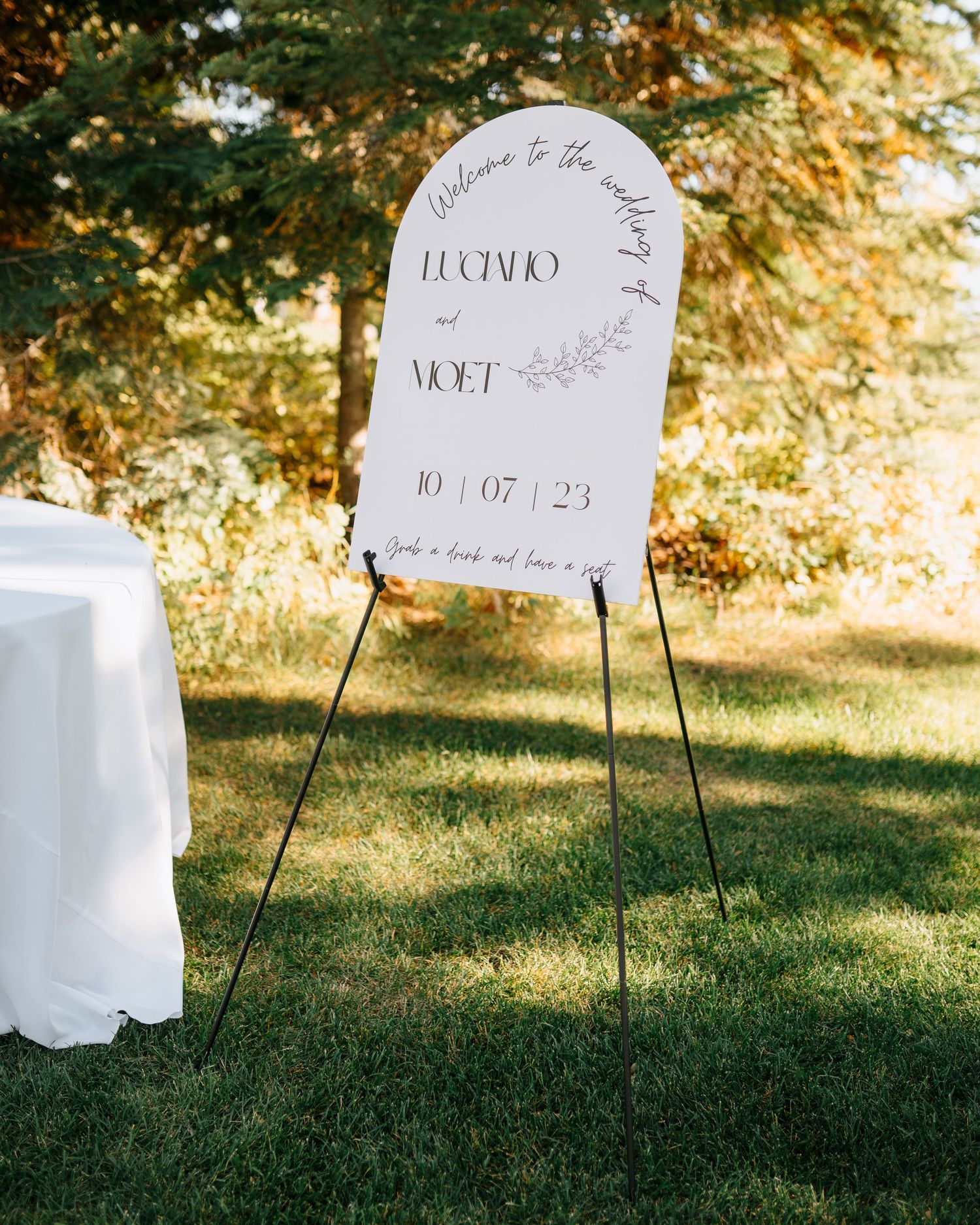Wedding signage displayed on stands in sunny outdoor garden setting.