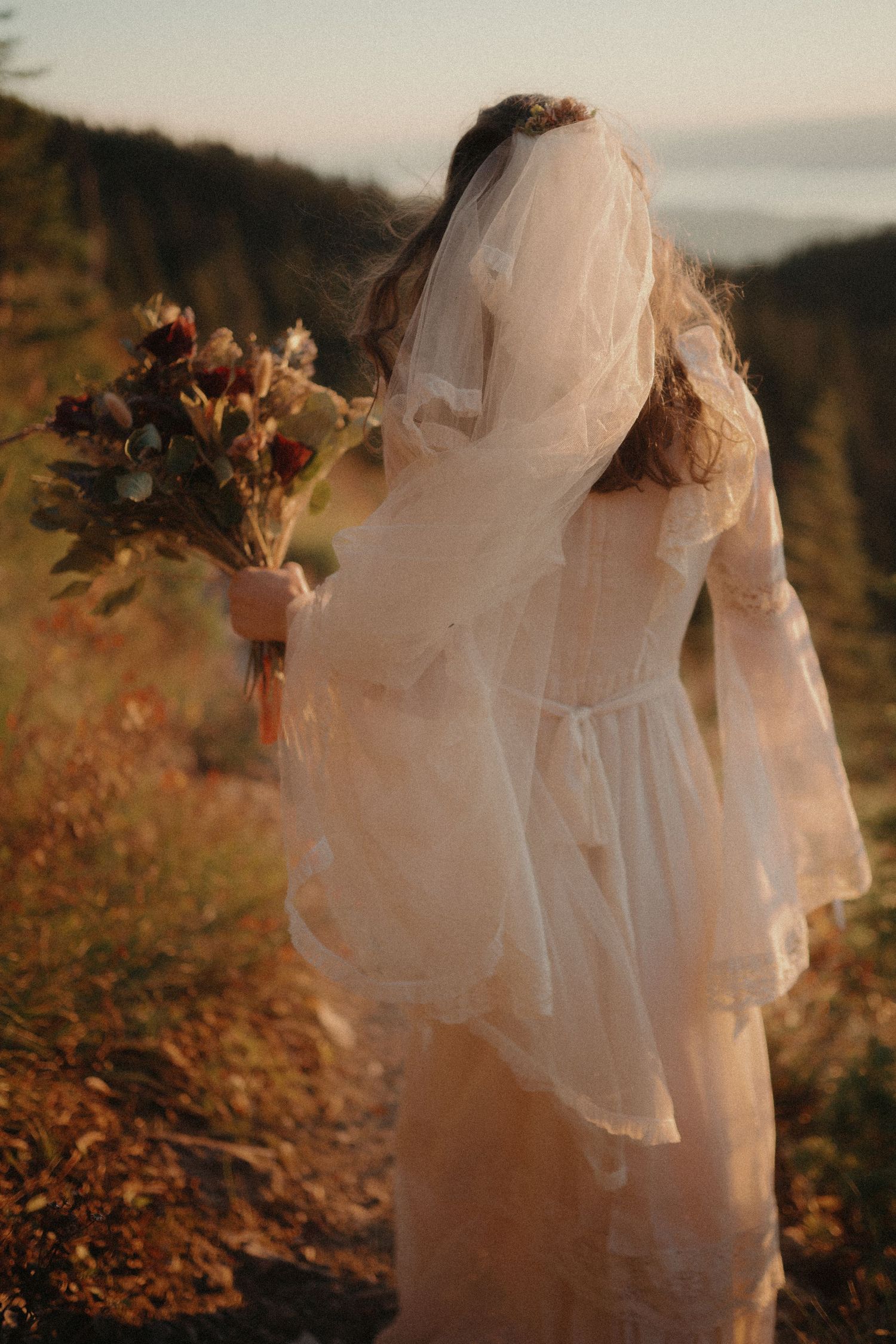 A dreamy autumn scene with a person in a flowing white dress and veil holding a bouquet against a golden sunset.