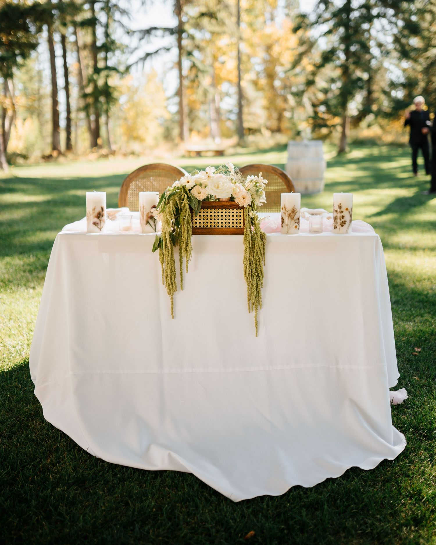 Elegant white tablecloth reception setup outdoors with natural greenery decor.