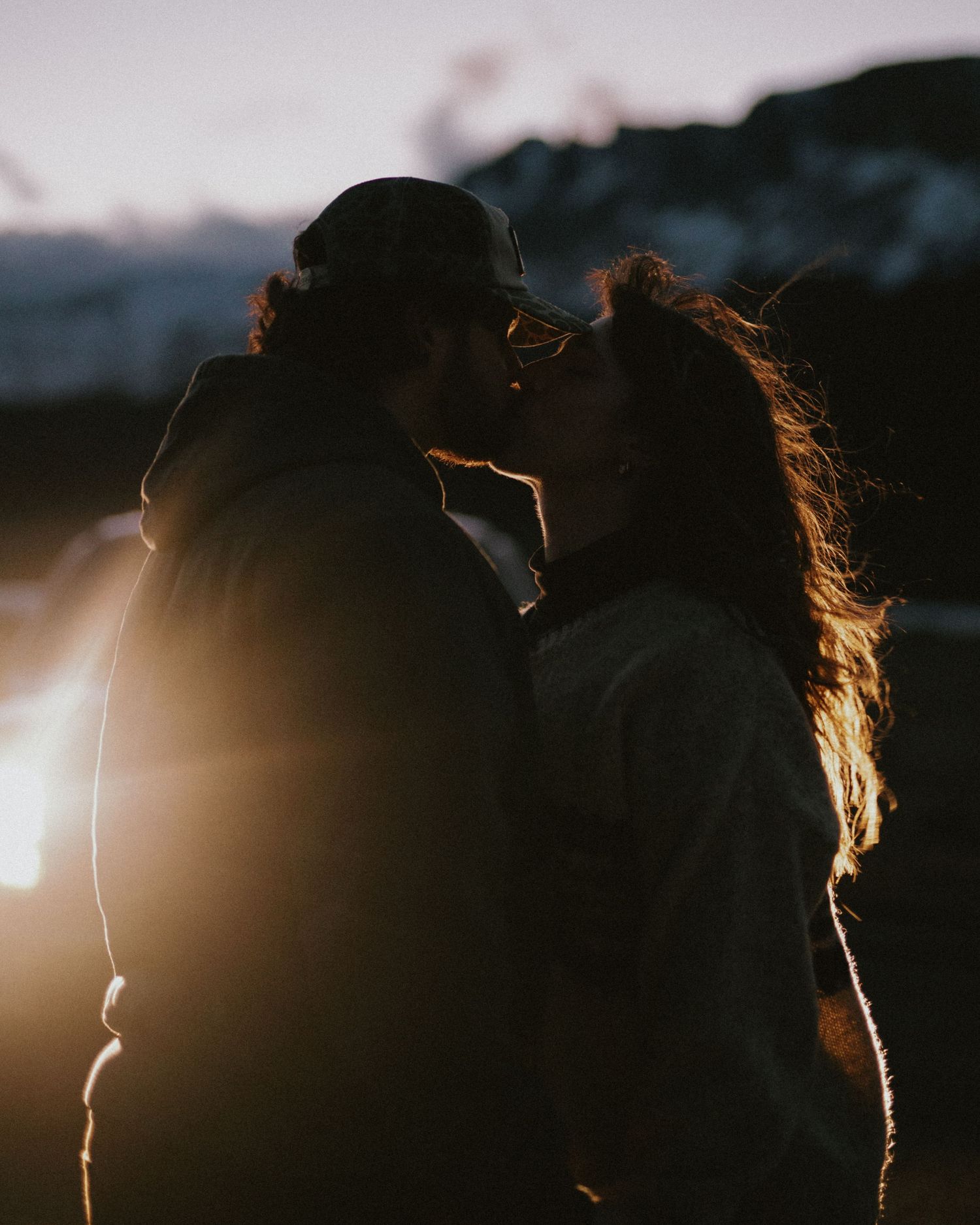 Two silhouetted figures embracing in the warm glow of the sunset.