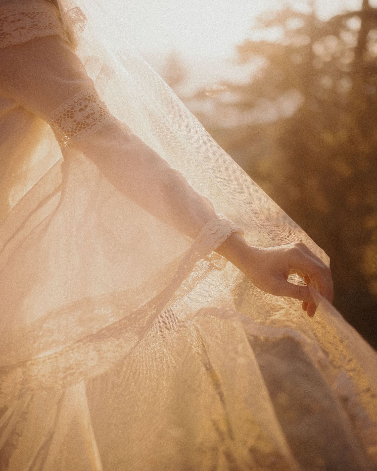Close-up view of delicate white lace fabric with intricate floral patterns in warm sunlight creating a dreamy effect.