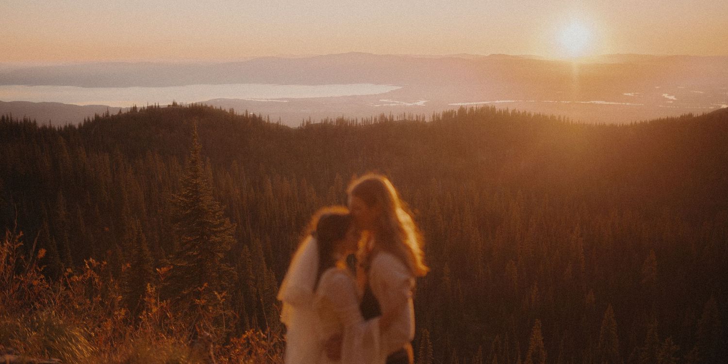 A golden sunset illuminates a misty mountain landscape with silhouetted trees and rolling hills in the distance.