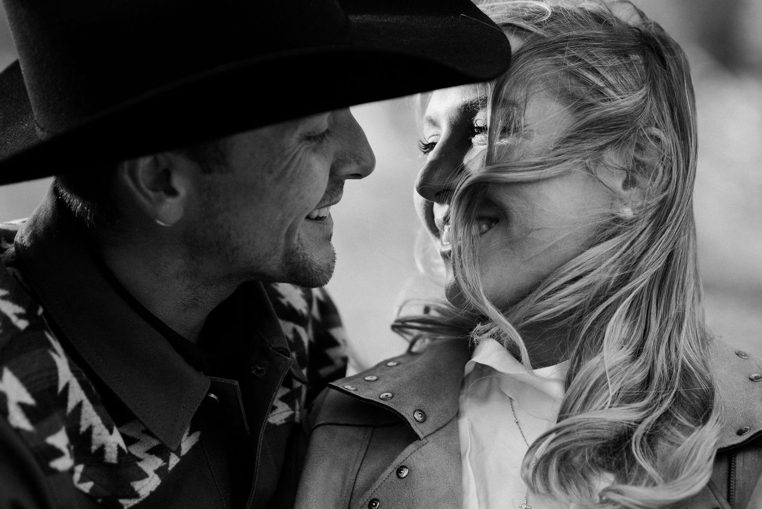 Montana Engagement photography of a couple smiling at each other with their faces leaning in close.