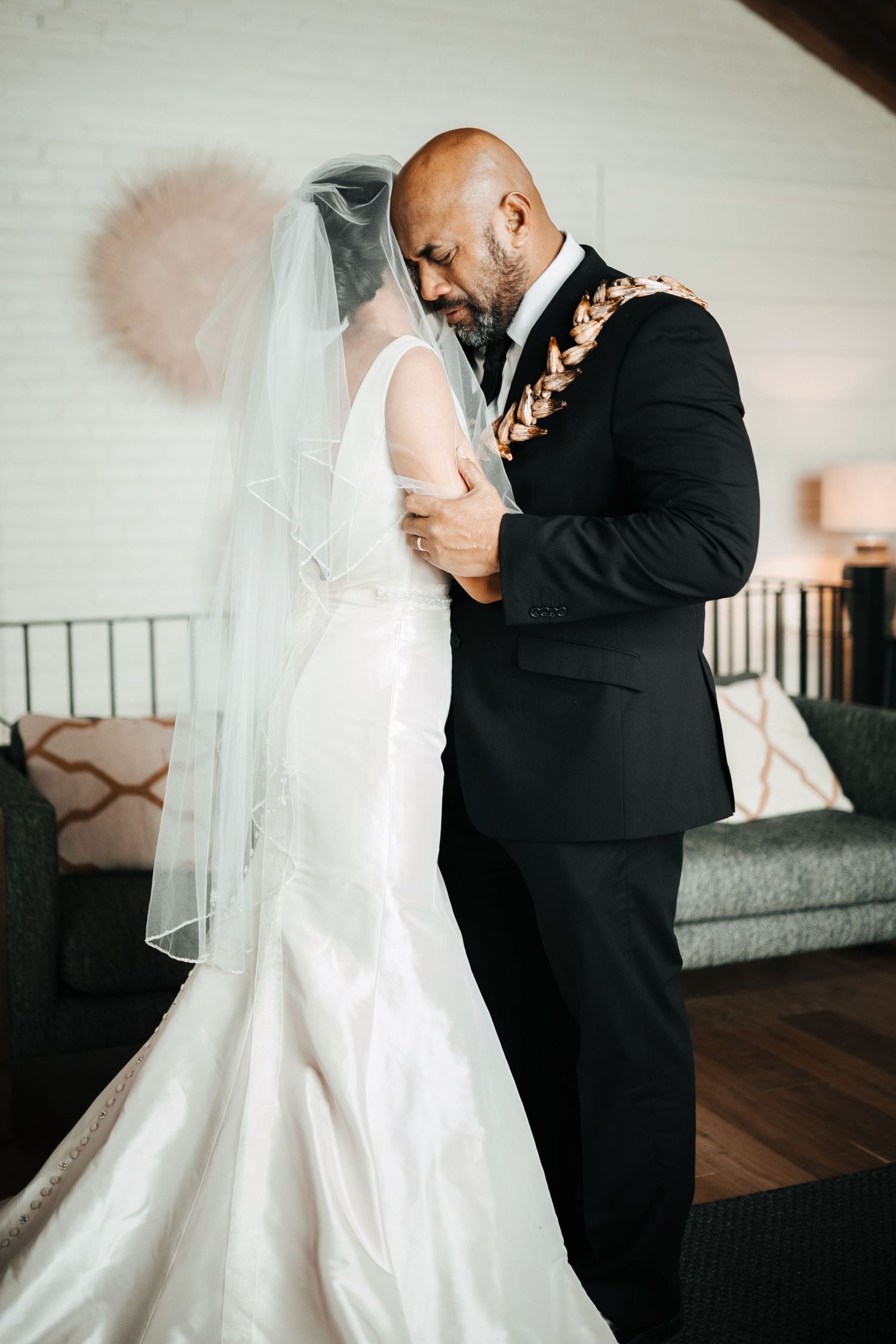 A touching first look moment between a bride in white and groom in black suit during their wedding day.