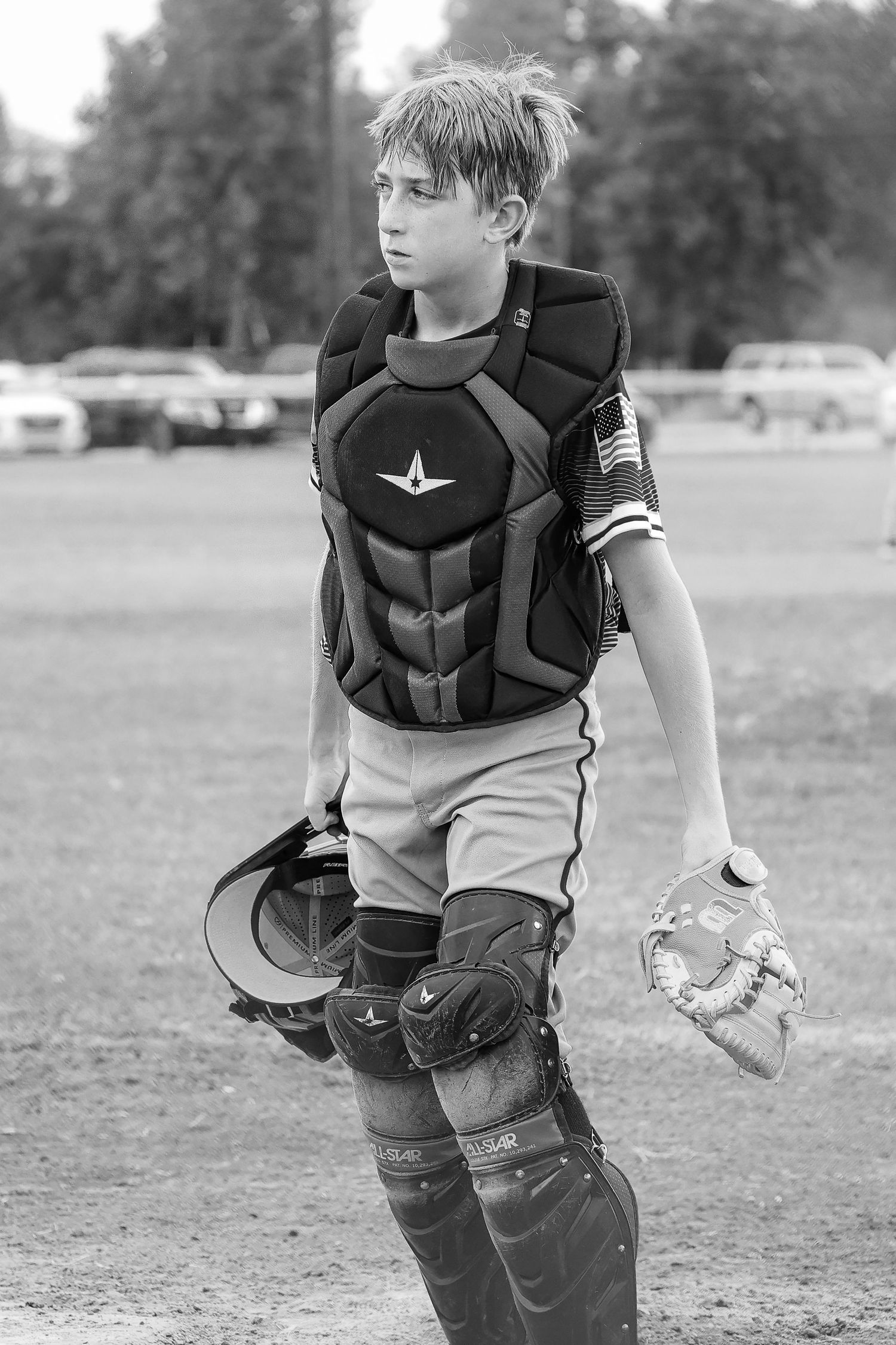 Black and white series of a young baseball catcher in protective gear practicing on a field.