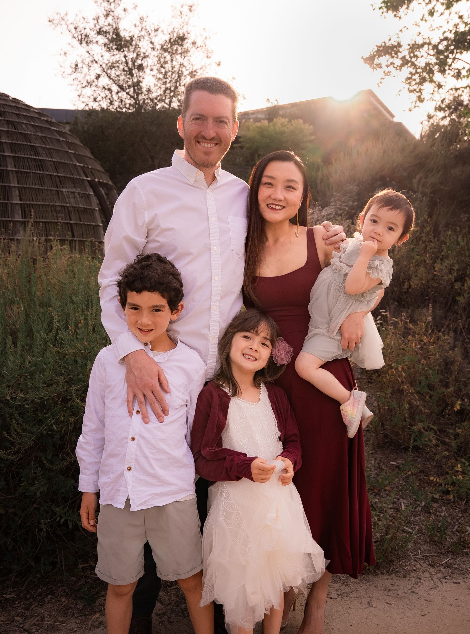a smiling portrait of a family of five during golden hour all smiling at the camera
