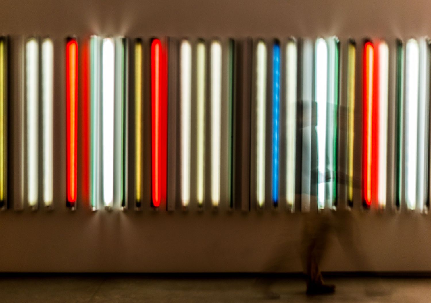 a motion blurred photo of a person walking in front of colorful vertical lights