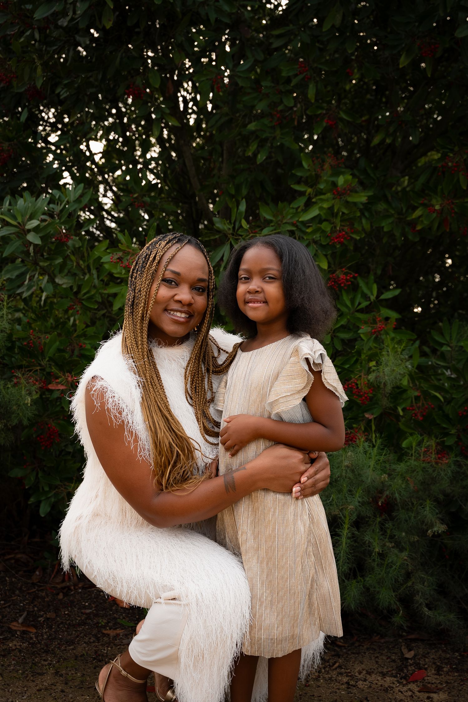 a mother and daughter dressed up in white and gold smiling at the camera