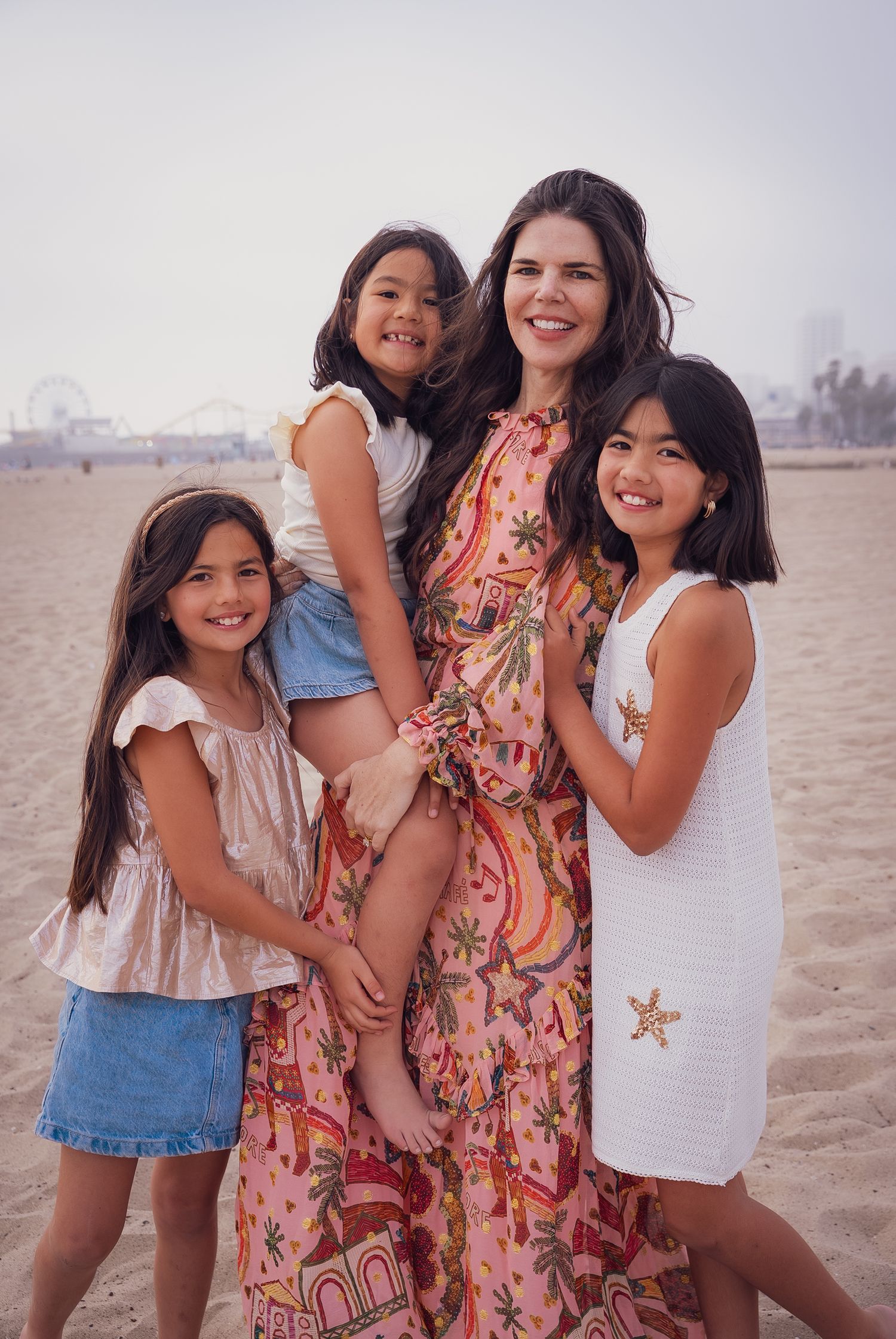 a portrait of a mother and her three daughters smiling at the camera at the beach