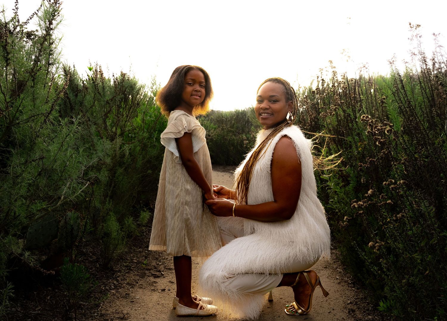 a mother and daughter on a pathway in the park smiling at the camera