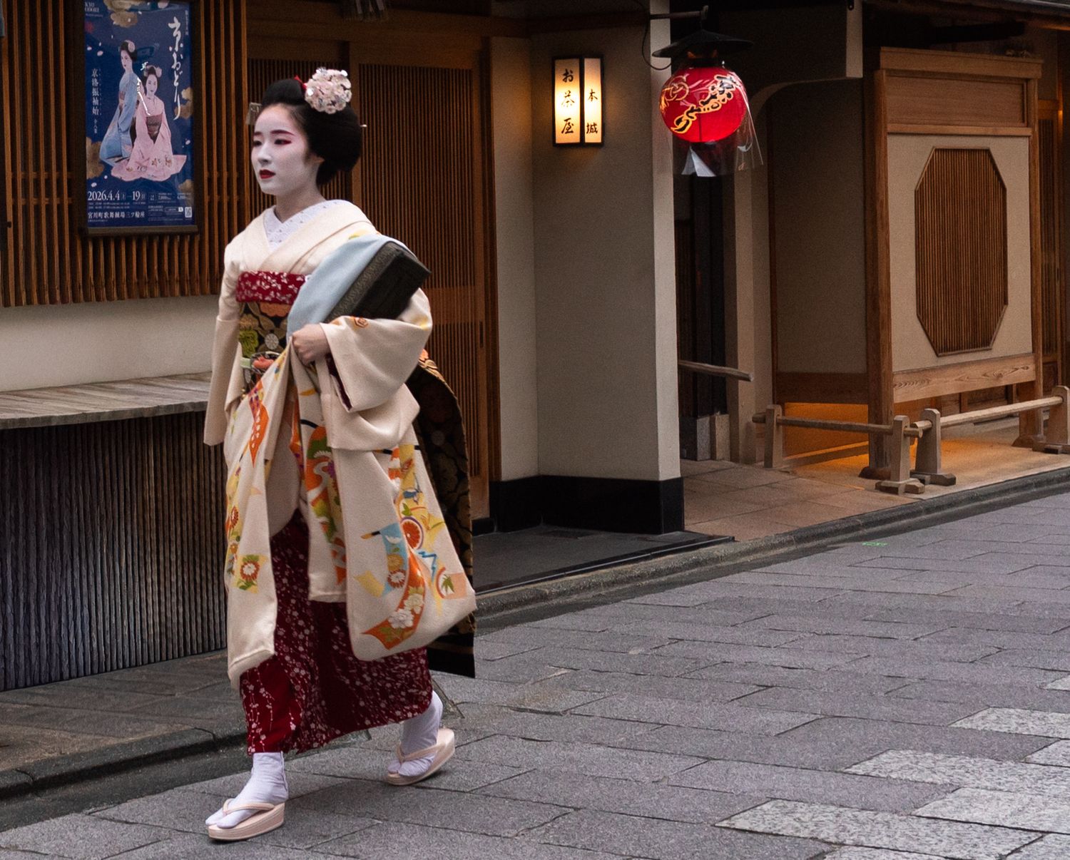a candid photo of a geisha walking on a pedestrian path in Gion, Kyoto on her way to a teahouse