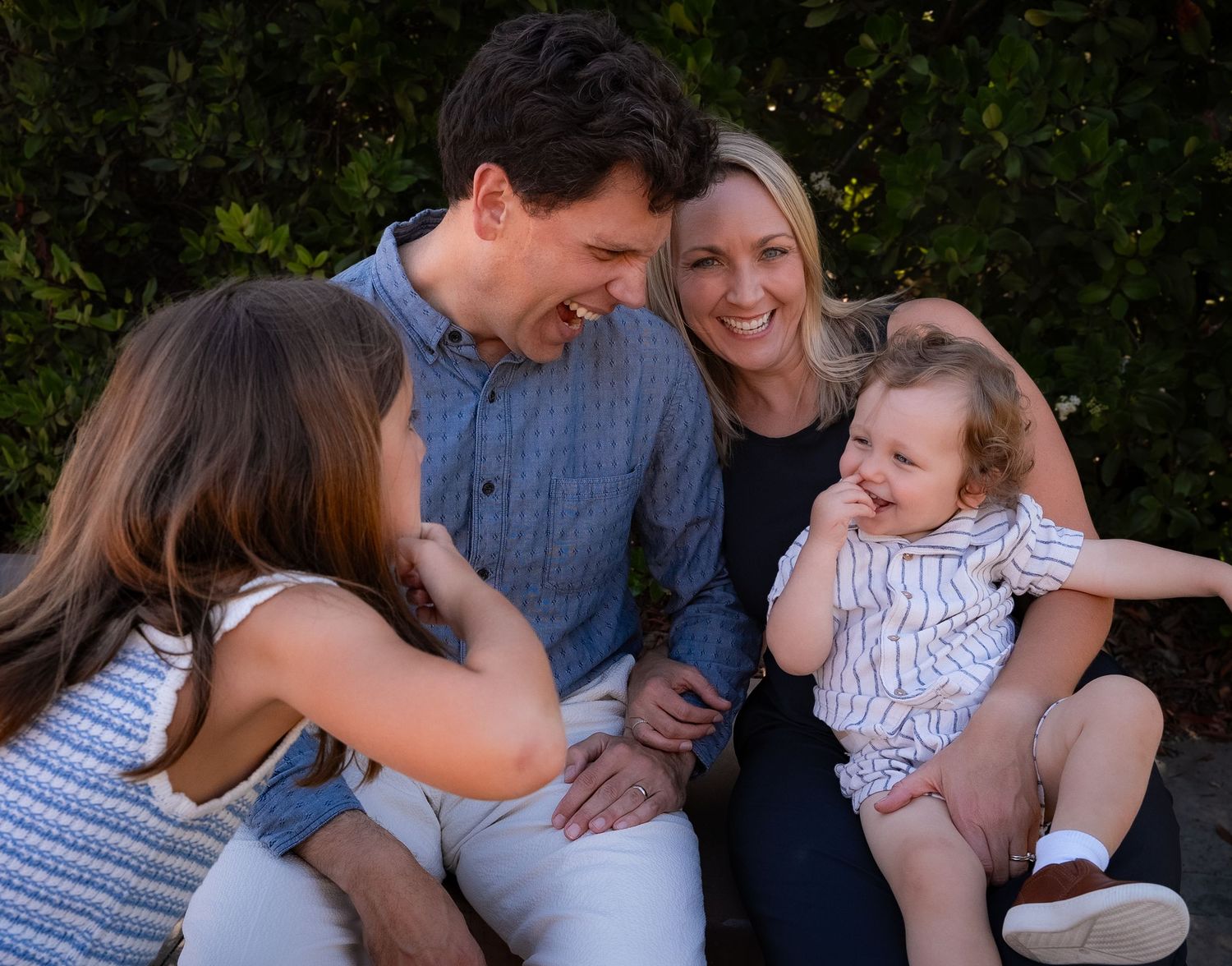 A candid smiling family portrait of a family of four making funny faces at each other in playa vista