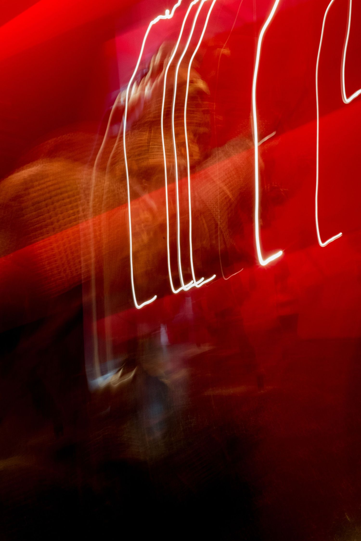 an abstract photo of a red background and lights in motion blur with the suggestion of a gold figure in the background