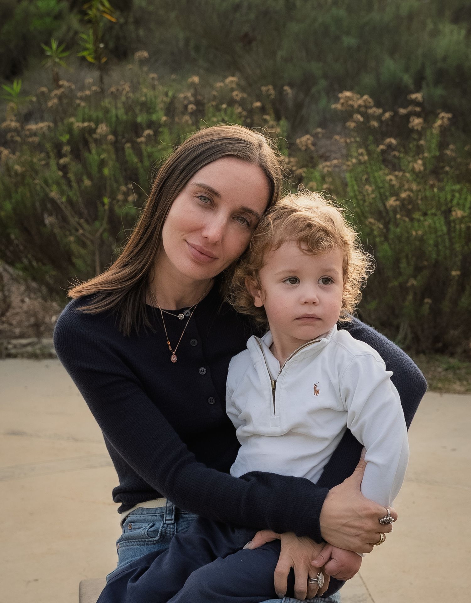 a sweet portrait of a mom hugging her toddler son who looks off into the distance