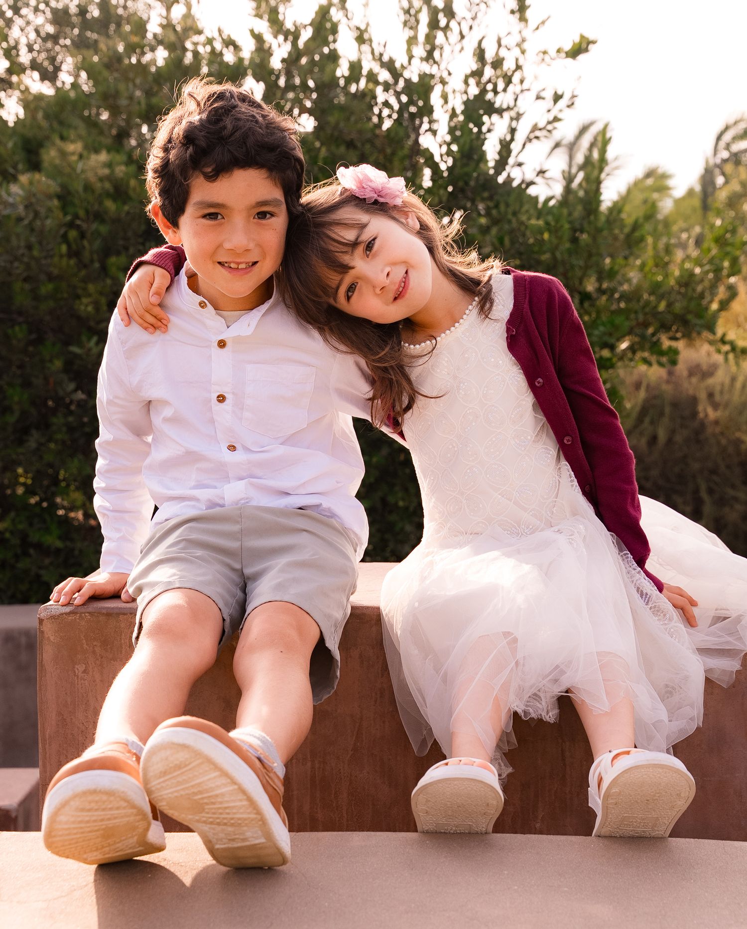 a sweet photo of a sister with her head on her brother's shoulder while they both smile at the camera