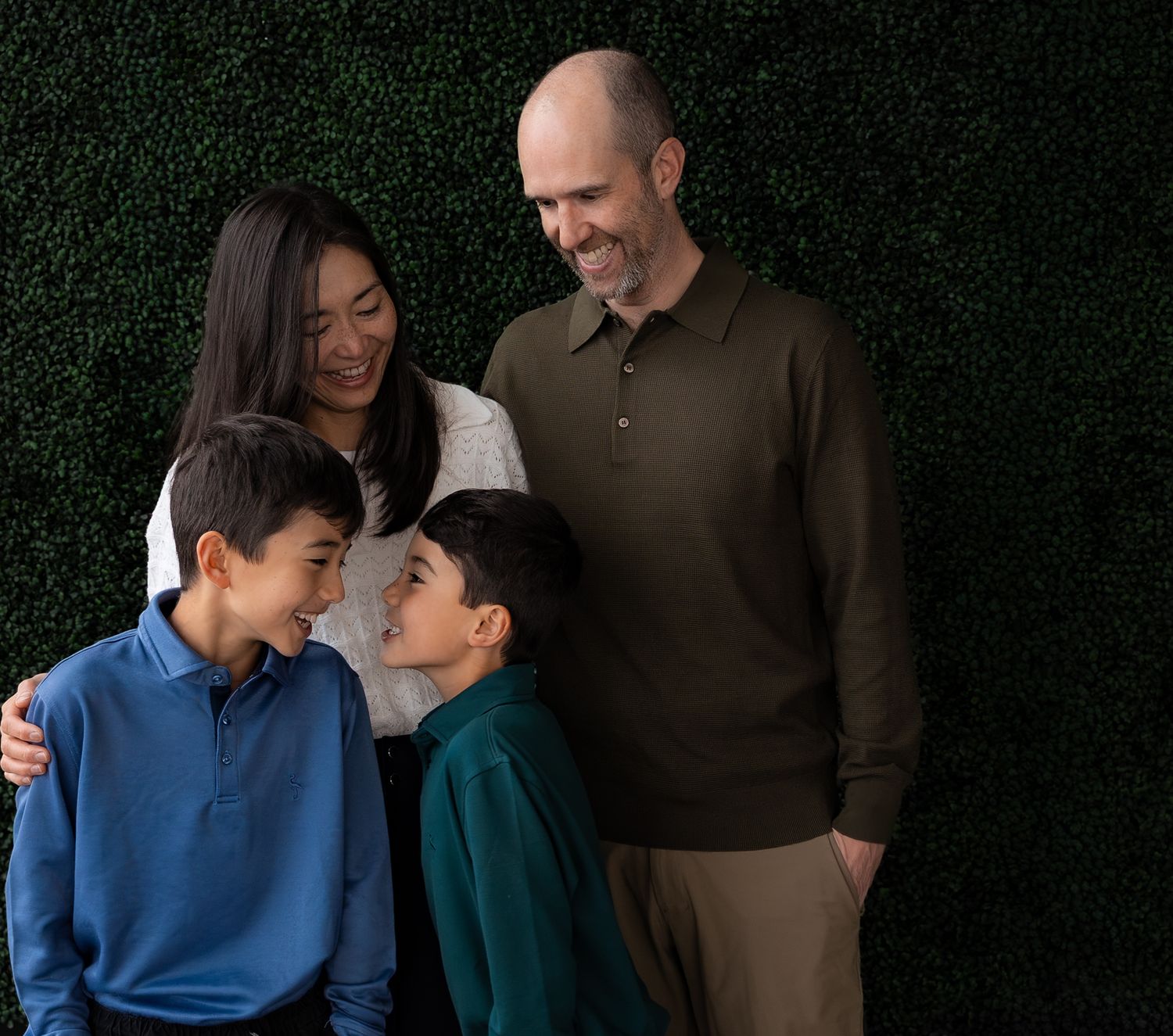 a candid photo of a family of four where the two boys are laughing at each other and their parents look at them lovingly