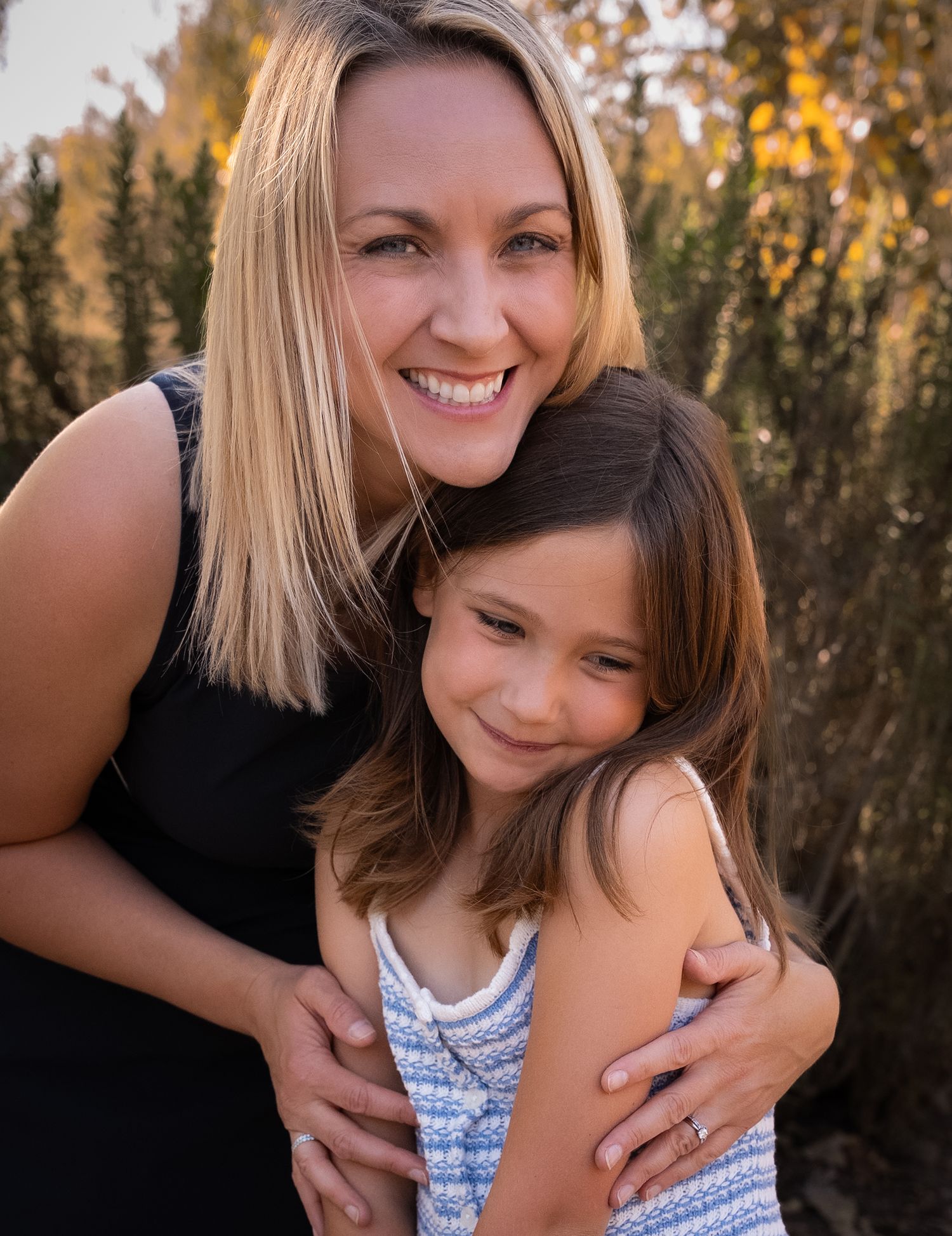 a sweet picture of a mother hugging her daughter from behind during golden hour