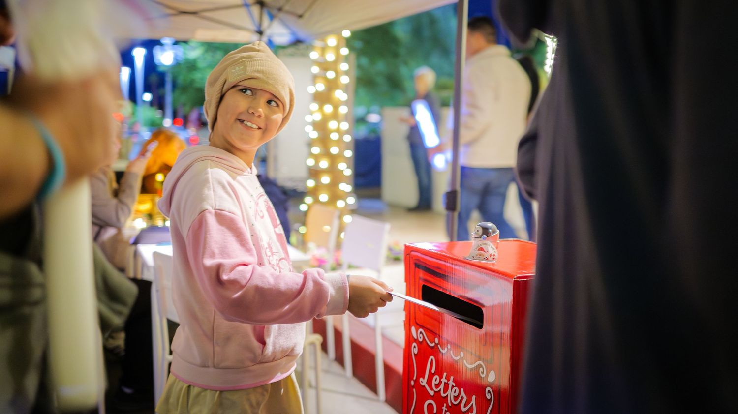 Holiday market scene with twinkling lights and festive decorations at night.