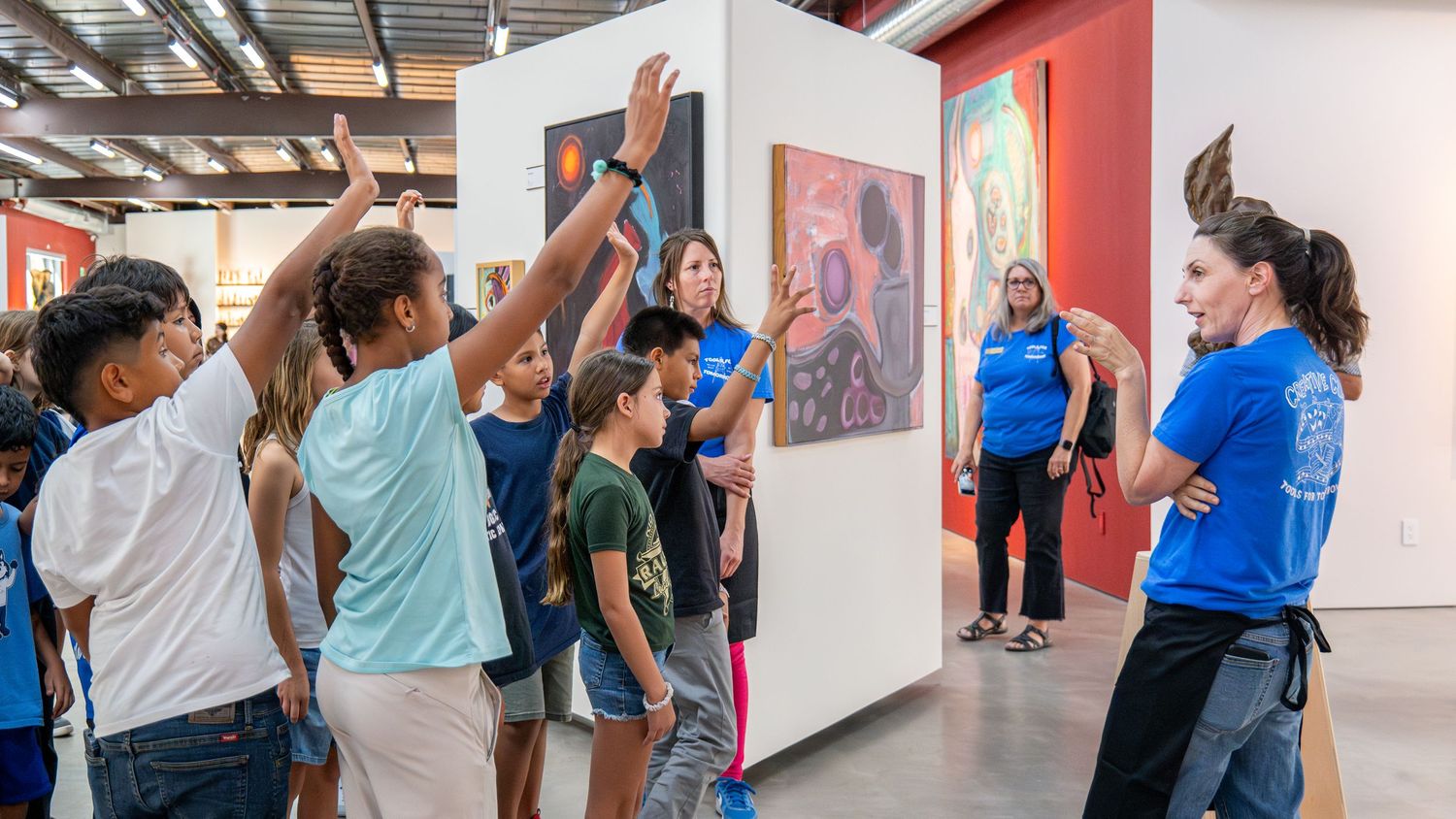 Large group of attendees participating in an interactive presentation in a spacious gallery space.