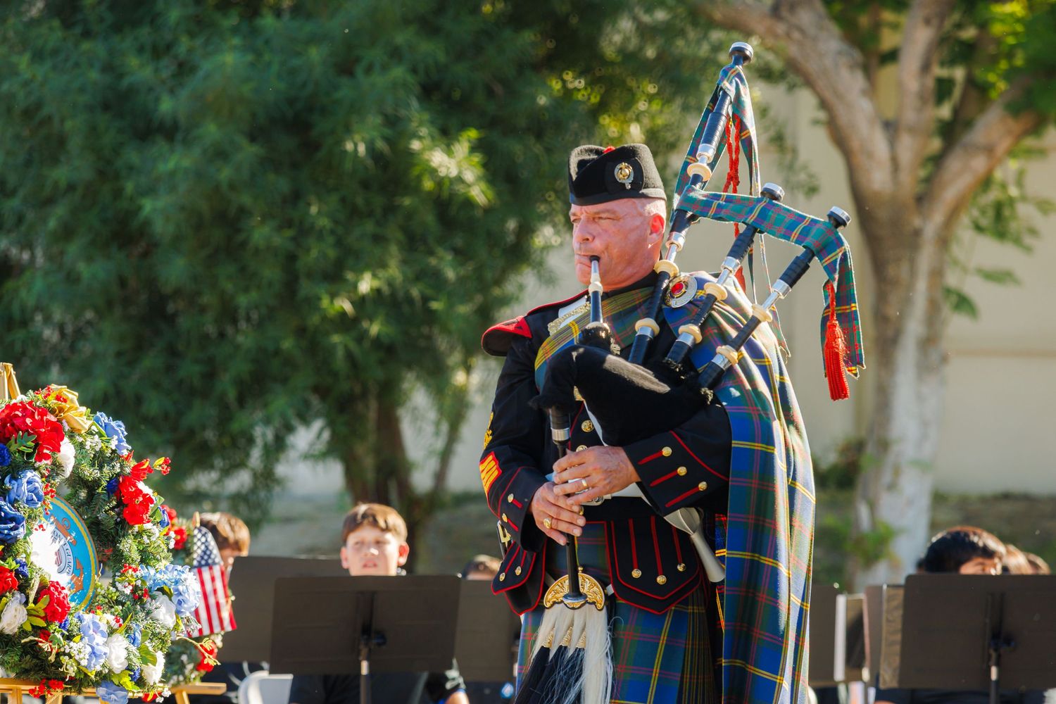 Outdoor celebration with American flags and decorative elements under trees.