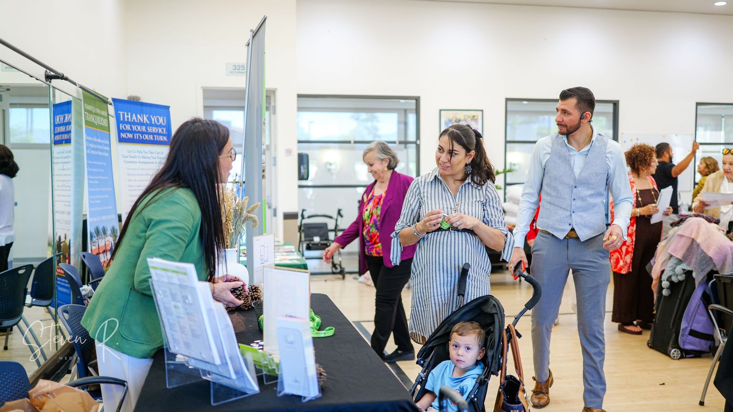 People networking and viewing displays at a professional conference in a modern venue.