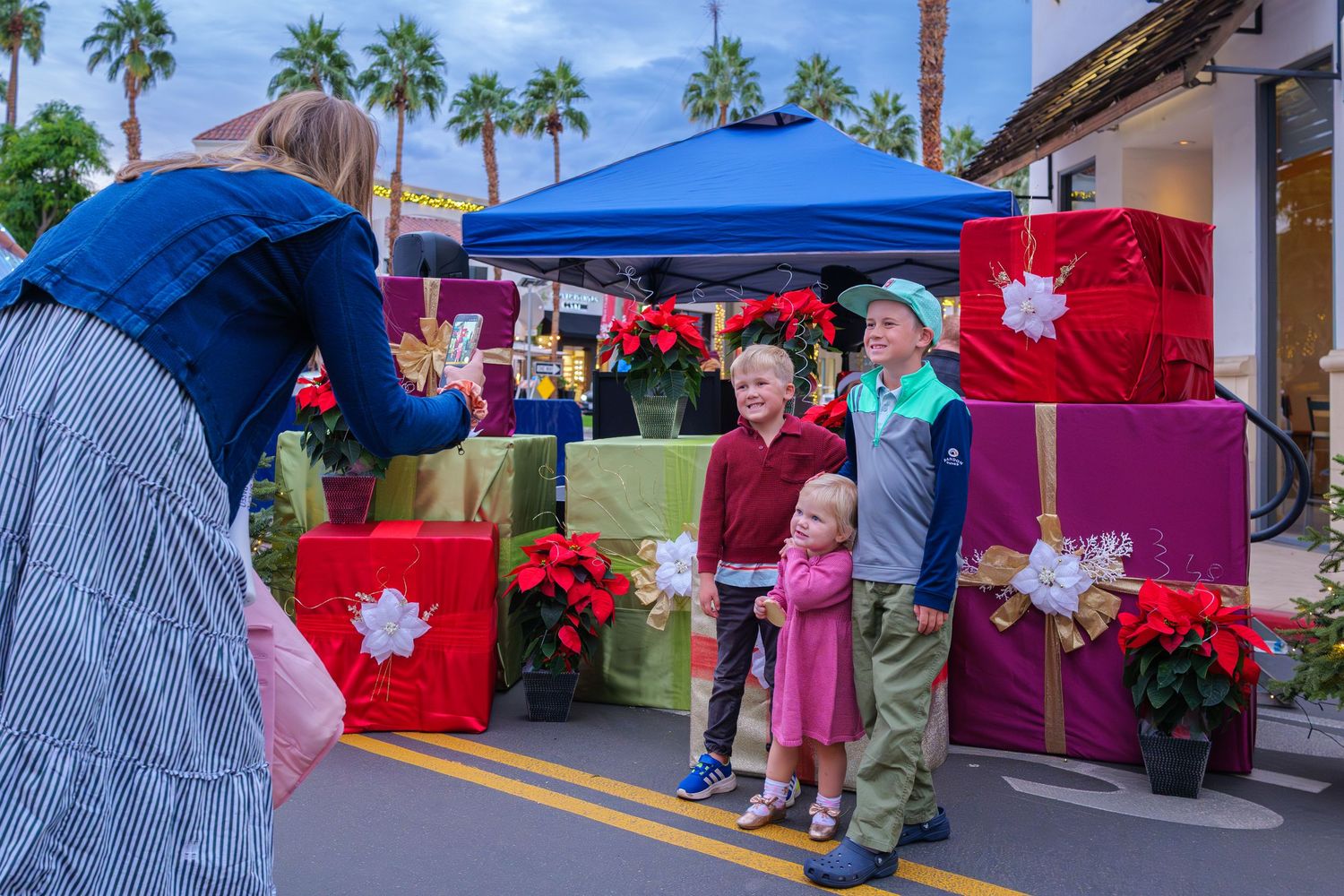 Outdoor market stalls with colorful canopies and palm trees lining a street.