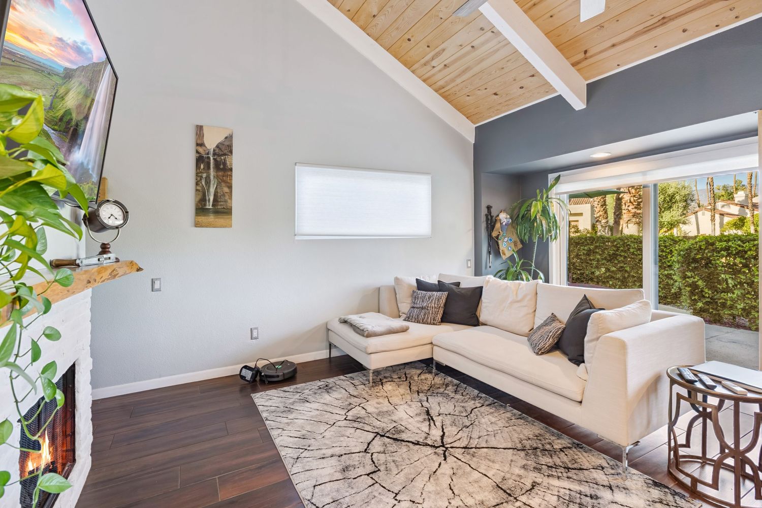 Modern living room with vaulted wood ceiling, grey walls, and large windows showcasing a bright, airy design.