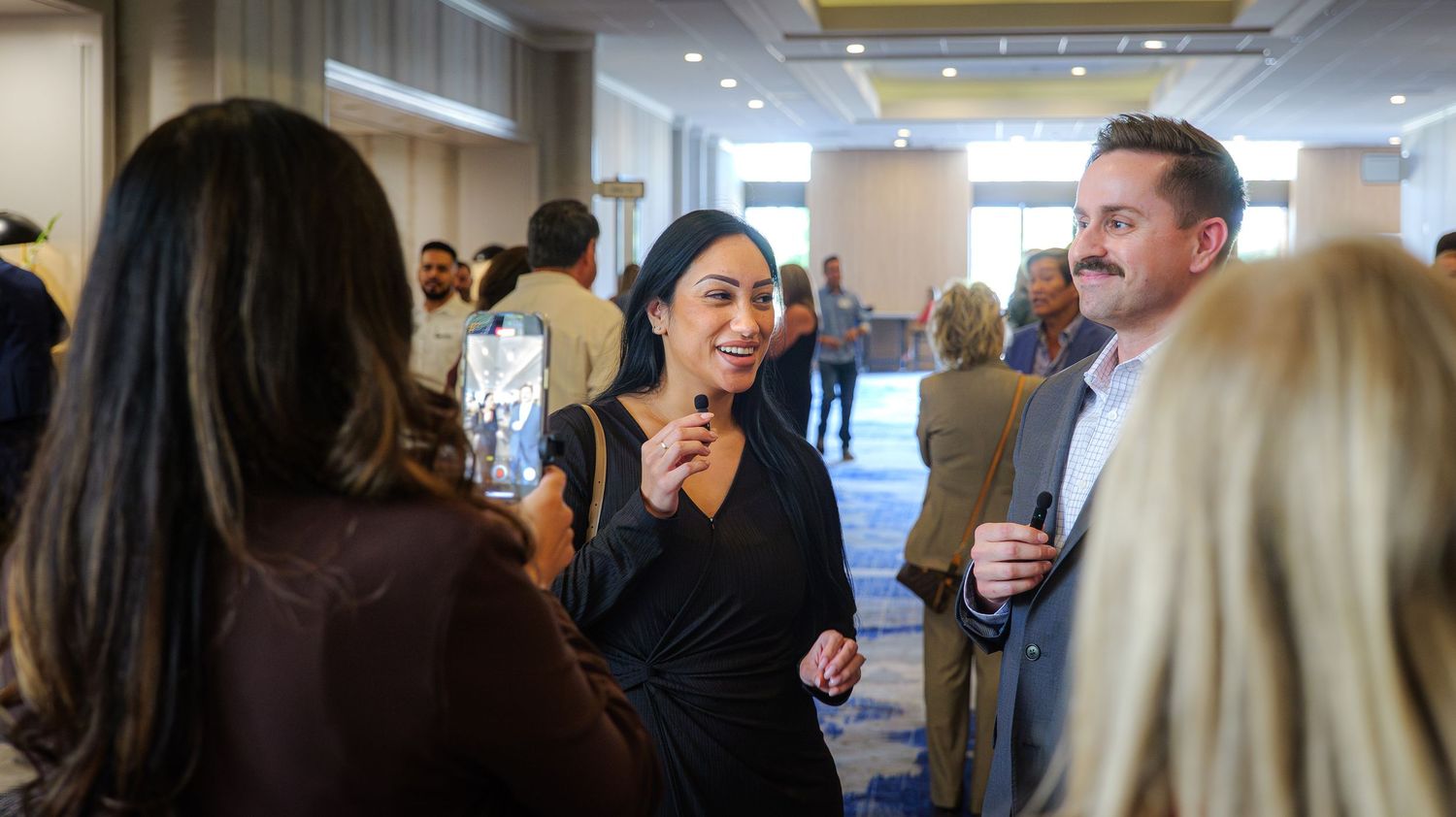 A panoramic view of people mingling and networking at a professional conference in a modern office space.