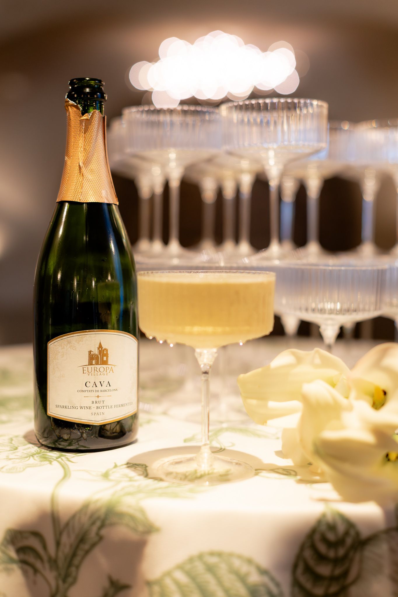 Elegant champagne bottles and glasses arranged on a white tablecloth with soft, romantic lighting and reflections. Wedding details. Elegant.