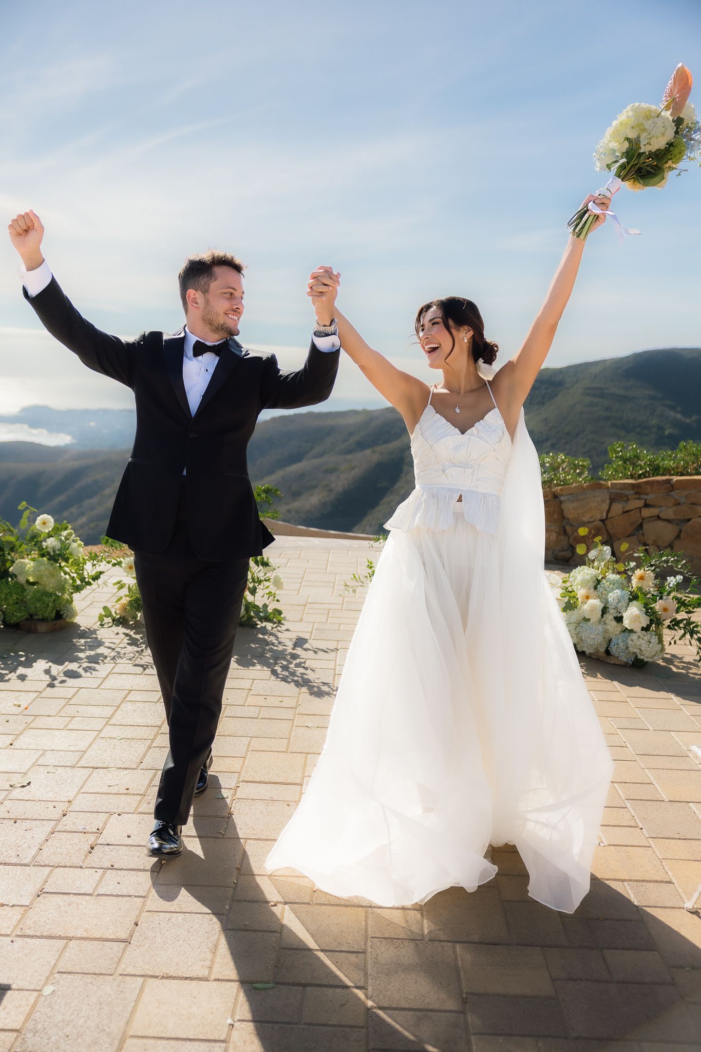 bride and groom celebrate after their cliffside wedding ceremony.