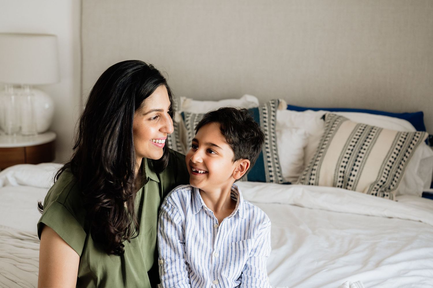 Candid family moment captured on white bedding with neutral decor.